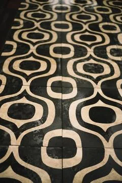 Black tile floor with a pattern of white rounded shapes. Stock Photos