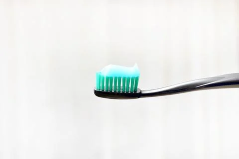 Black toothbrush with toothpaste applied to it on a light background Stock Photos