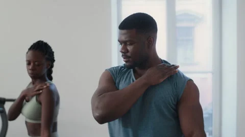 Black Trainer Demonstrating Arm Circle Exercise to Woman in Gym Video stock 305454580