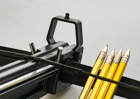 Black training crossbow with a black string and four arrows on a white back.. Stock Photos