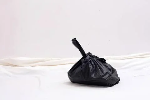 Black trash bag on white surface with plain background Stock Photos