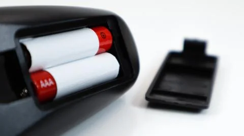 Black TV remote control with AAA alkaline batteries in red and white on a whi Fotos Stock