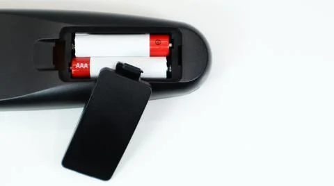 Black TV remote control with AAA alkaline batteries in red and white on a whi Stock-Fotos