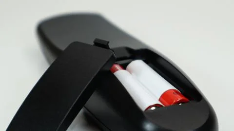 Black TV remote control with AAA alkaline batteries in red and white on a whi Fotos Stock