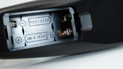 Black TV remote control with AAA alkaline batteries on a white background. Ba Fotos Stock