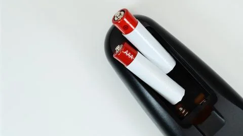 Black TV remote control with AAA alkaline batteries on a white background. Ba Stock-Fotos