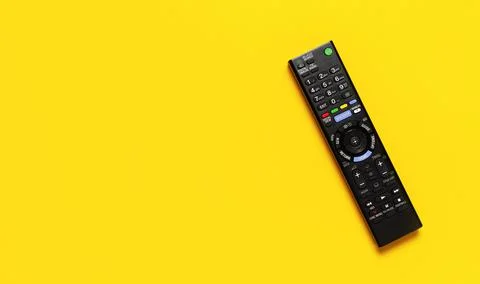 Black TV remote control on bright yellow background flat lay top view Stock Photos