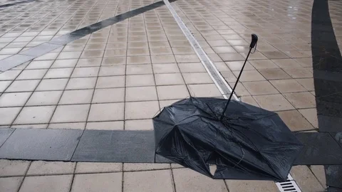 Black umbrella lying on the sidewalk in the rain Stock Footage 79414964