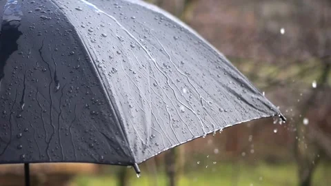 A black umbrella outside, raindrops hitting and scattering on its surface i.. Video stock 264597232