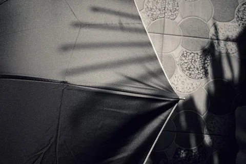 Black umbrella with shadows on patterned tiled floor Stock Photos