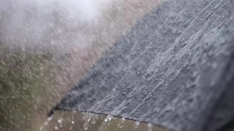 A black umbrella under siege by rain, slow-motion droplets splashing upon i.. Stock-Footage 265586281
