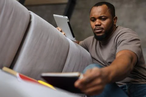 Black unshaven man using tablet computer while working at home Foto stock