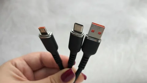 A black USB charging cable in the hand. The cable has a standard USB connector Stock Footage 317668339