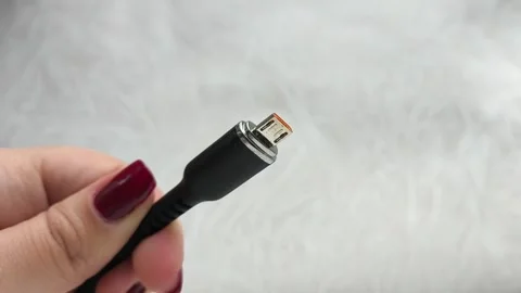 A black USB charging cable in the hand. The cable has a standard micro USB Stock Footage 317668408