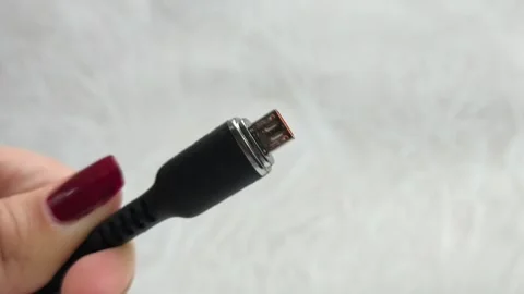 A black USB charging cable in the hand. The cable has a standard micro USB Stock Footage 317668415