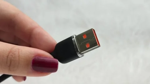 A black USB charging cable in the hand. The cable has a standard USB Stock Footage 317668524