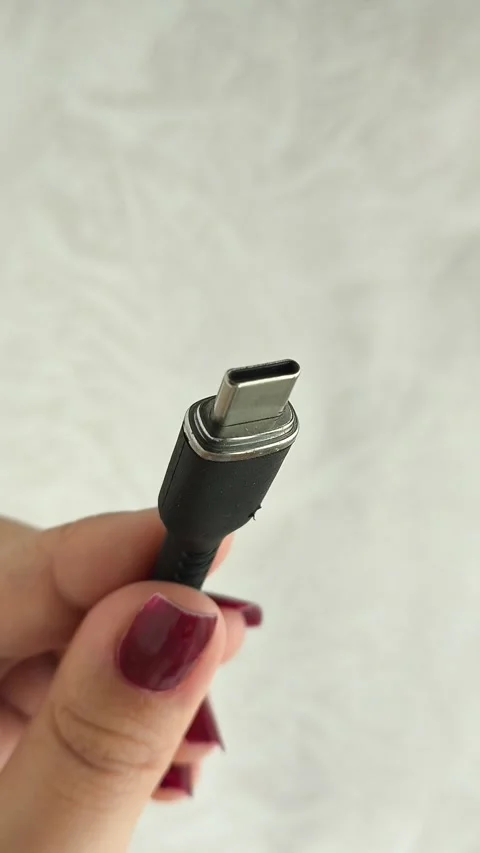 A black USB charging cable in the hand. The cable has a standard type-c Stock Footage 317668751