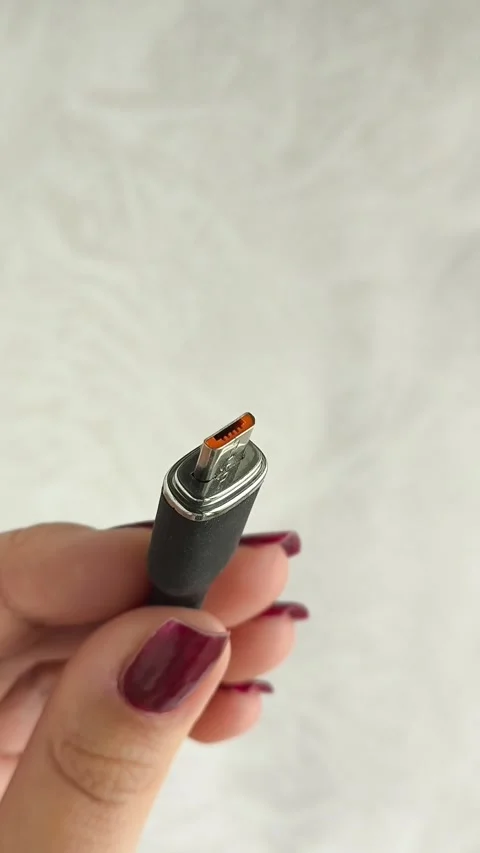 A black USB charging cable in the hand. The cable has a standard micro USB Video stock 317668872