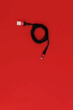 Black usb cord on red background, subject technology Stock Photos