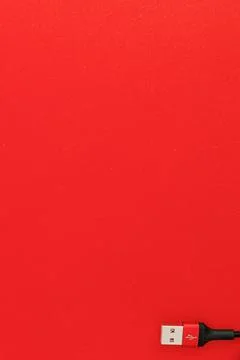 Black usb cord on red background, subject technology Stock Photos