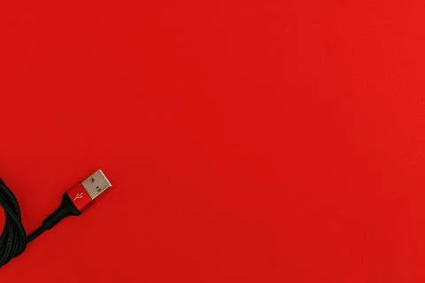 Black usb cord on red background, subject technology Stock Photos
