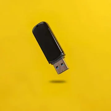 Black usb flash drive floating on yellow background Stock Photos