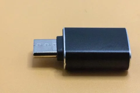 A black USB OTG adapter with a micro USB connector is shown on a tan surface. 스톡 사진