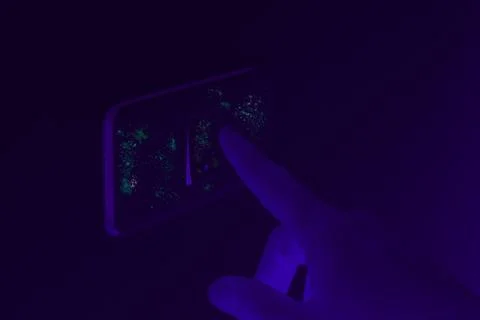 Black UV light exposing germs and bacteria on hand touching lighting switch - Stock Photos