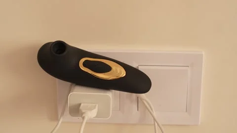 Black vacuum vibrator charging on the bedside table. Adult toys Stock Footage 319831100