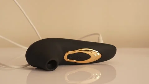 Black vacuum vibrator charging on the bedside table. Adult toys Stock Footage 319831146