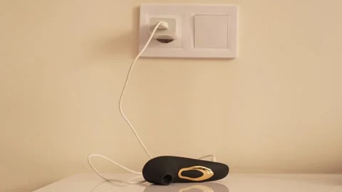 Black vacuum vibrator charging on the bedside table. Adult toys Stock Footage 319831255