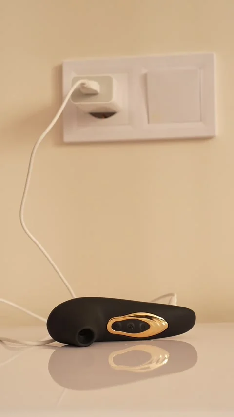 Black vacuum vibrator charging on the bedside table. Adult toys Stock Footage 319831580