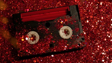 Black video cassette on the background of red glitter Stock Footage 99989128