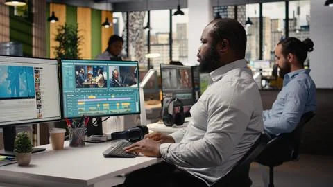 Black videographer editing raw video footage and adjusting sliders on software Stock Photos