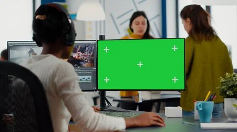 Black videographer with headphones using computer with green screen Stock Photos