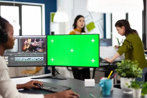 Black videographer with headphones using computer with green screen Stock Photos