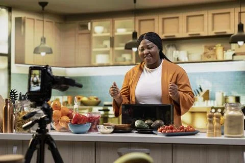 Black vlogger recording cooking tutorial and preparing avocado for a dish 写真素材
