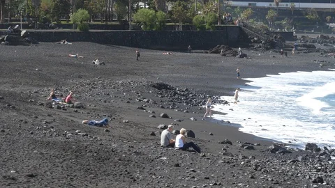 Black volcanic sand beach with ocean waves and people leisure in Tenerife Stock Footage 86207869