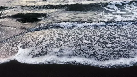 Black volcanic sand beach. Waves roll in one after another Stock-Footage 141246946