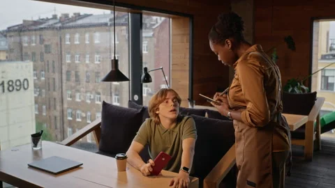 Black Waitress Taking Order from Man in Modern Coffee Shop 動画素材 344368396