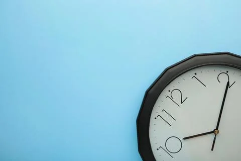 Black wall clock on the blue background. Stock Photos
