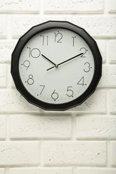 Black wall clock on the white wall background. Stock Photos