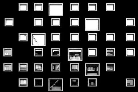 Black wall featuring blank frames and greyscale photos of different places Stock Photos