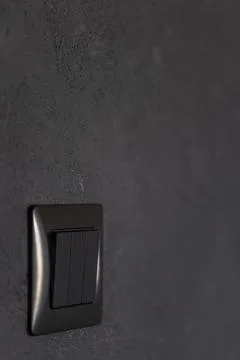 Black wall switch on textured dark wall. Vertical interior detail with copy.. Stock Photos