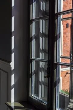 Black window frame with many shadows inside on the wall. Light streaming Stock Photos