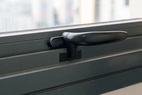 Black window handle on dark gray window frame Stock Photos
