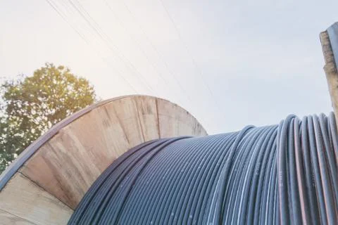 Black wire  electric cable with wooden coil of electric cable under the sky. Foto stock