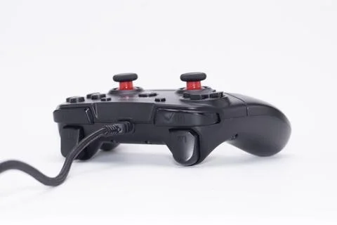 Black Wired Game Controller with Red Joysticks on White Background, Side View Stock Photos