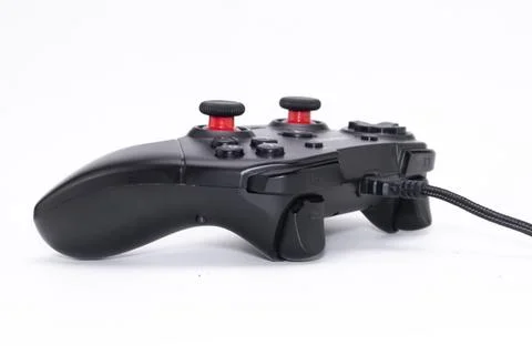 Black Wired Game Controller with Red Accents on White Background, Side View. Stock Photos
