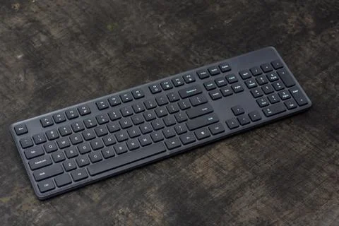 Black wireless computer keyboard on a dark concrete table. Stock Photos